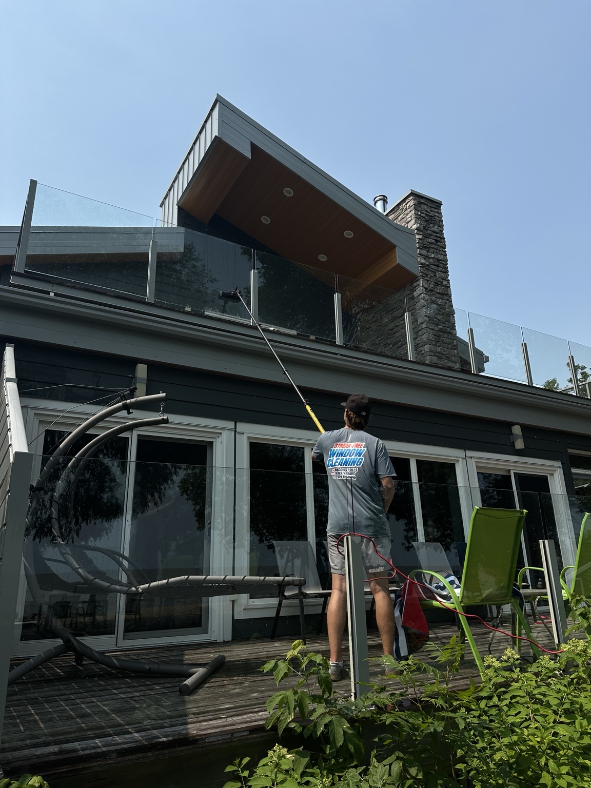 Newmar cleaning upper glass railings and windows with a professional water-fed pole
